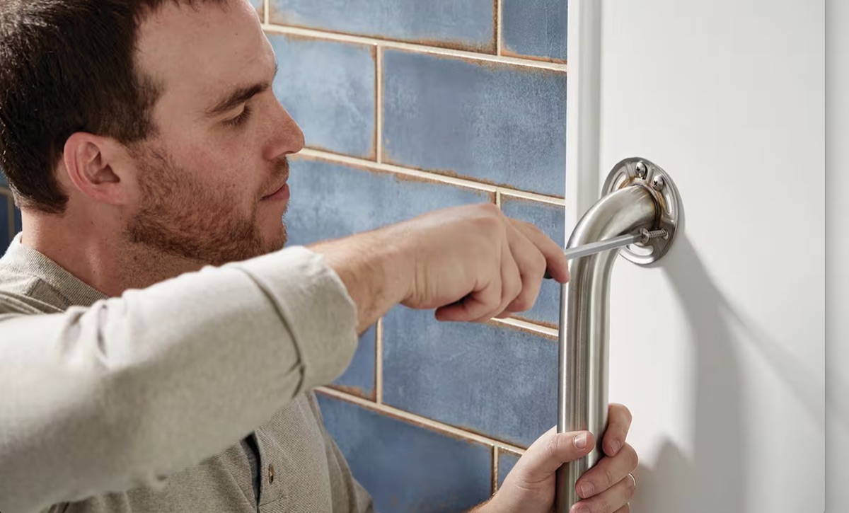 Installer securing a grab bar to a bathroom wall